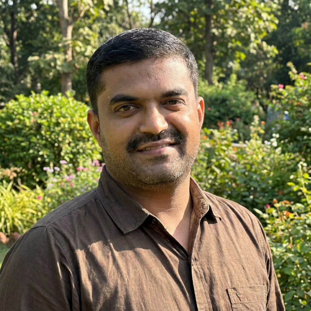 A man in a brown shirt standing in a sun-dappled garden.