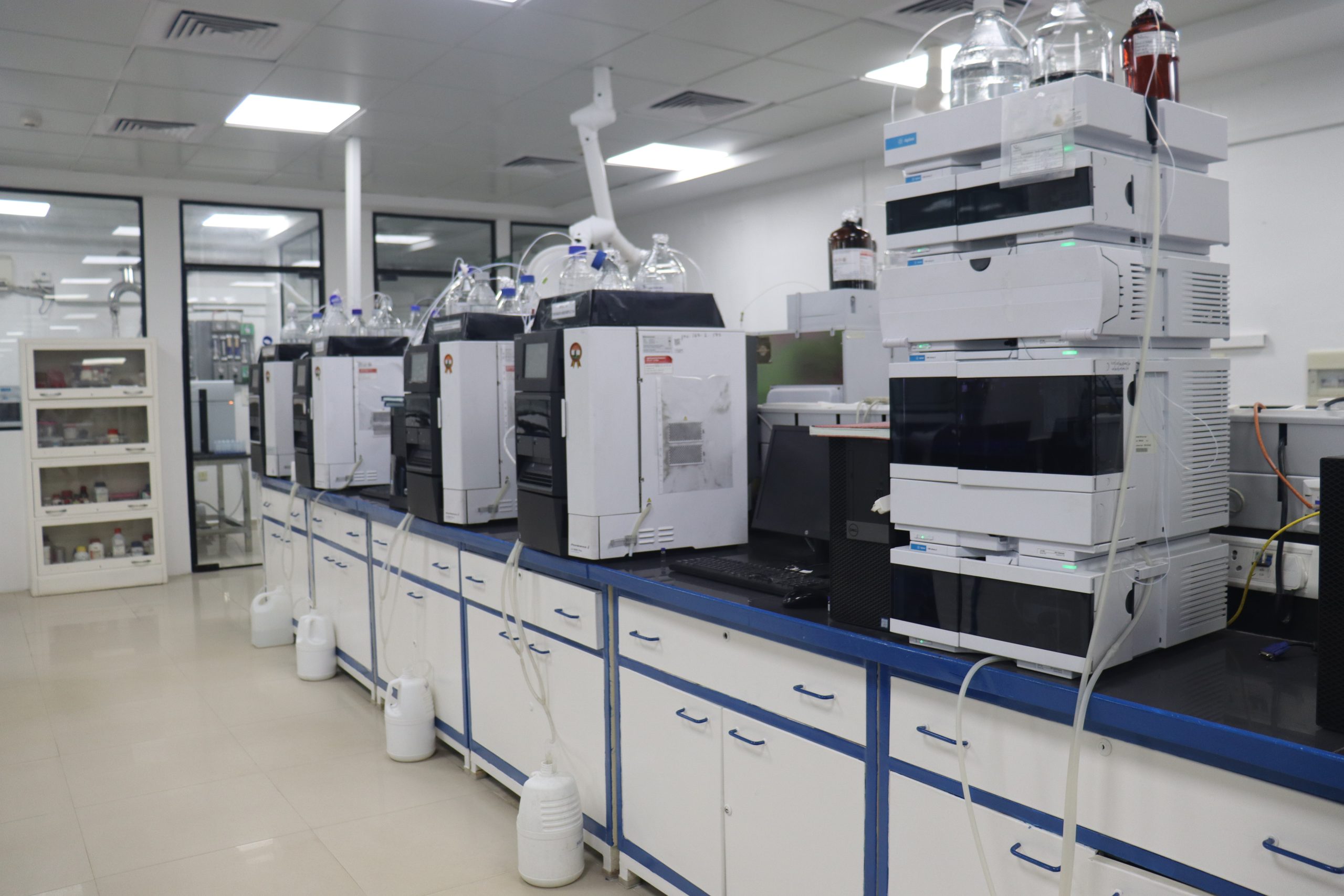 A row of HPLC instruments on lab benches in an analytical laboratory